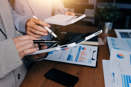 Group of confident business people point to graphs and charts to analyze market data, balance sheet, account, net profit to plan new sales strategies to increase production capacity.の写真素材