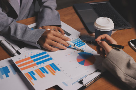Group of confident business people point to graphs and charts to analyze market data, balance sheet, account, net profit to plan new sales strategies to increase production capacity.の写真素材