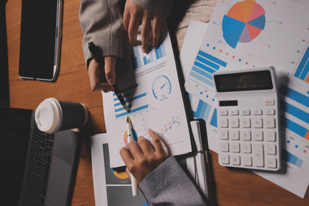 Group of confident business people point to graphs and charts to analyze market data, balance sheet, account, net profit to plan new sales strategies to increase production capacity.の写真素材