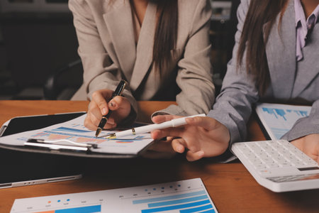 Group of confident business people point to graphs and charts to analyze market data, balance sheet, account, net profit to plan new sales strategies to increase production capacity.の写真素材