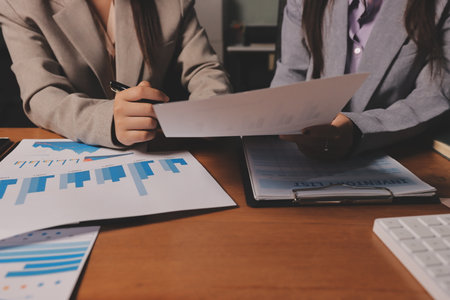 Group of confident business people point to graphs and charts to analyze market data, balance sheet, account, net profit to plan new sales strategies to increase production capacity.の写真素材