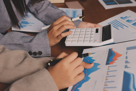 Group of confident business people point to graphs and charts to analyze market data, balance sheet, account, net profit to plan new sales strategies to increase production capacity.の写真素材