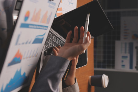 Group of confident business people point to graphs and charts to analyze market data, balance sheet, account, net profit to plan new sales strategies to increase production capacity.の写真素材