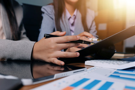 Group of confident business people point to graphs and charts to analyze market data, balance sheet, account, net profit to plan new sales strategies to increase production capacity.の写真素材