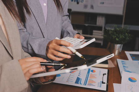 Group of confident business people point to graphs and charts to analyze market data, balance sheet, account, net profit to plan new sales strategies to increase production capacity.の写真素材