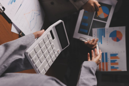 Group of confident business people point to graphs and charts to analyze market data, balance sheet, account, net profit to plan new sales strategies to increase production capacity.の写真素材