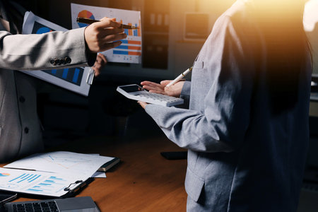 Group of confident business people point to graphs and charts to analyze market data, balance sheet, account, net profit to plan new sales strategies to increase production capacity.の写真素材