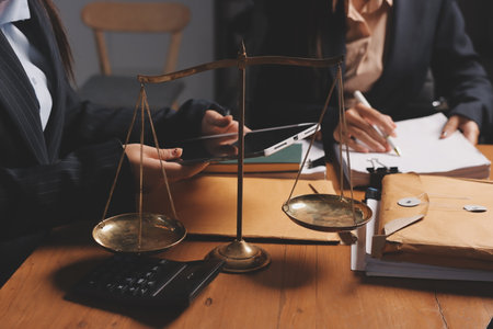 Attractive young lawyer in office Business woman and lawyers discussing contract papers with brass scale on wooden desk in office. Law, legal services, advice, Justice and real estate concept.の写真素材