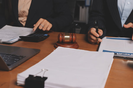 Attractive young lawyer in office Business woman and lawyers discussing contract papers with brass scale on wooden desk in office. Law, legal services, advice, Justice and real estate concept.の写真素材