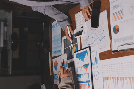 Group of confident business people point to graphs and charts to analyze market data, balance sheet, account, net profit to plan new sales strategies to increase production capacity.の写真素材