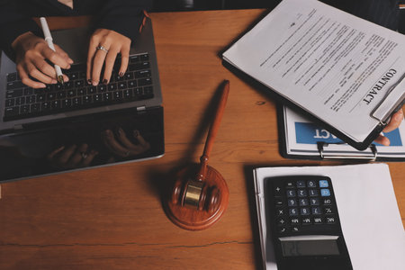Attractive young lawyer in office Business woman and lawyers discussing contract papers with brass scale on wooden desk in office. Law, legal services, advice, Justice and real estate concept.の写真素材