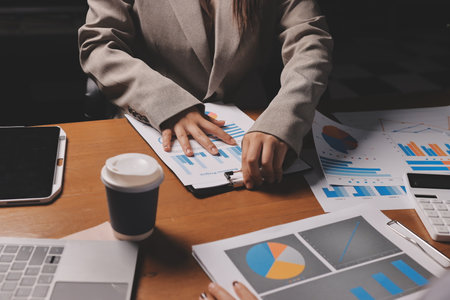 Group of confident business people point to graphs and charts to analyze market data, balance sheet, account, net profit to plan new sales strategies to increase production capacity.の写真素材