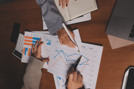 Group of confident business people point to graphs and charts to analyze market data, balance sheet, account, net profit to plan new sales strategies to increase production capacity.の写真素材