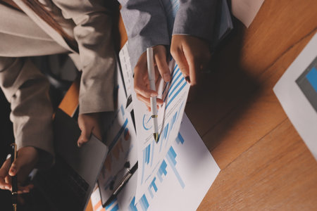 Group of confident business people point to graphs and charts to analyze market data, balance sheet, account, net profit to plan new sales strategies to increase production capacity.の写真素材