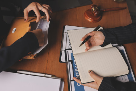 Attractive young lawyer in office Business woman and lawyers discussing contract papers with brass scale on wooden desk in office. Law, legal services, advice, Justice and real estate concept.の写真素材