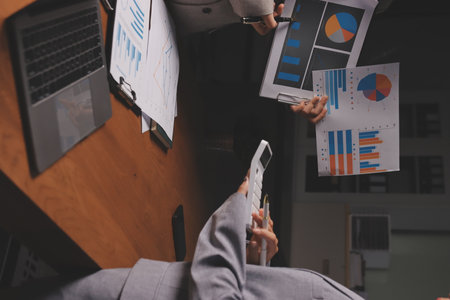 Group of confident business people point to graphs and charts to analyze market data, balance sheet,...