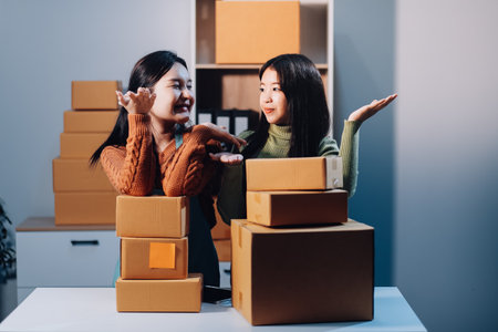 Startup SME small business entrepreneur of freelance Asian woman wearing apron using laptop and box to receive and review orders online to prepare to pack sell to customers, online sme business ideas.の写真素材