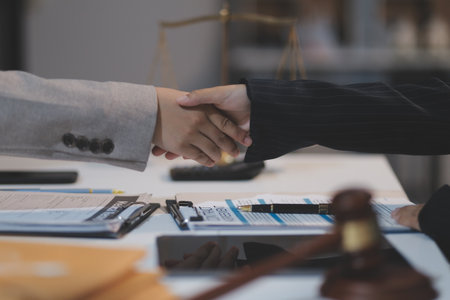 Lawyer shaking hands with a client making about documents, contracts, agreements, cooperation agreements with a female client at the lawyer's desk and a hammer at the table.の写真素材