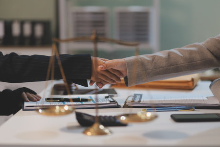Lawyer shaking hands with a client making about documents, contracts, agreements, cooperation agreements with a female client at the lawyer's desk and a hammer at the table.の写真素材