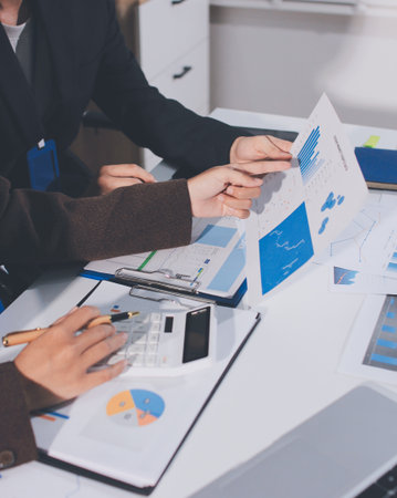 Focused young businessman signing agreement with skilled lawyer in eyeglasses. Concentrated financial advisor showing place for signature on paper contract document to male client at meeting in officeの写真素材