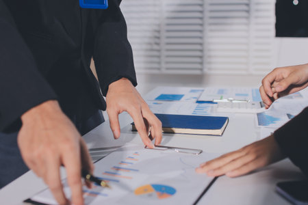 Focused young businessman signing agreement with skilled lawyer in eyeglasses. Concentrated financial advisor showing place for signature on paper contract document to male client at meeting in officeの写真素材