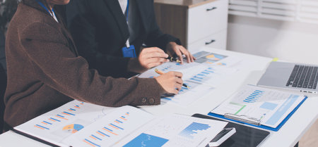 Focused young businessman signing agreement with skilled lawyer in eyeglasses. Concentrated financial advisor showing place for signature on paper contract document to male client at meeting in officeの写真素材