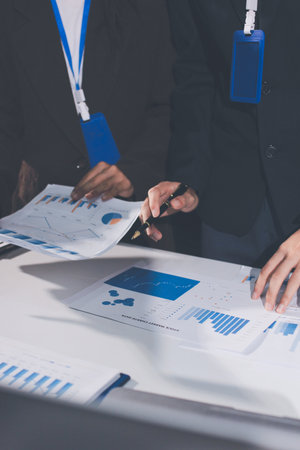 Focused young businessman signing agreement with skilled lawyer in eyeglasses. Concentrated financial advisor showing place for signature on paper contract document to male client at meeting in officeの写真素材