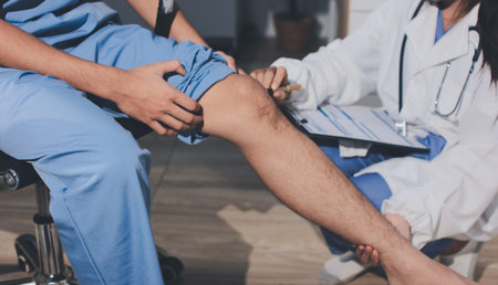 Physical therapist teaching a patient how to do exercises for his knee painの写真素材