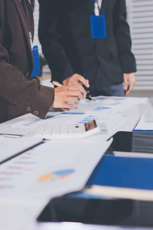 Focused young businessman signing agreement with skilled lawyer in eyeglasses. Concentrated financial advisor showing place for signature on paper contract document to male client at meeting in officeの写真素材