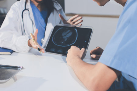 Cropped shot of an unrecognisable doctor sitting with his patient and showing her x-rays on a digital tabletの写真素材