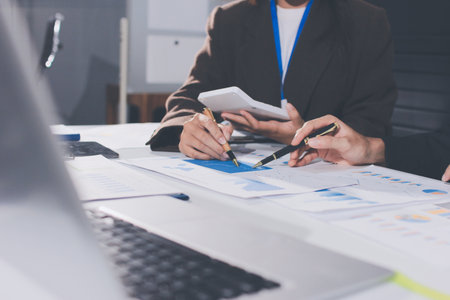 Focused young businessman signing agreement with skilled lawyer in eyeglasses. Concentrated financial advisor showing place for signature on paper contract document to male client at meeting in officeの写真素材