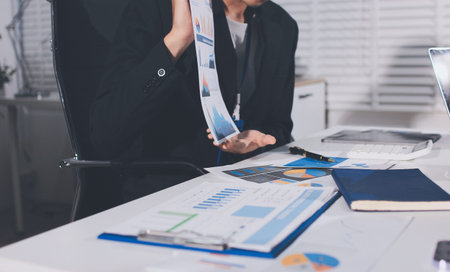 Focused young businessman signing agreement with skilled lawyer in eyeglasses. Concentrated financial advisor showing place for signature on paper contract document to male client at meeting in officeの写真素材