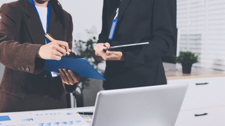 Focused young businessman signing agreement with skilled lawyer in eyeglasses. Concentrated financial advisor showing place for signature on paper contract document to male client at meeting in officeの写真素材