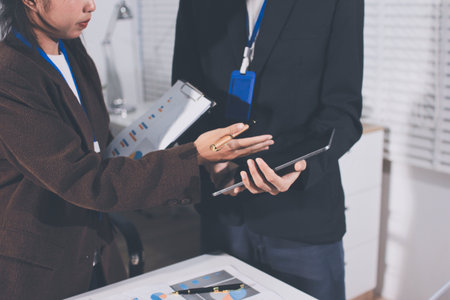 Focused young businessman signing agreement with skilled lawyer in eyeglasses. Concentrated financial advisor showing place for signature on paper contract document to male client at meeting in officeの写真素材