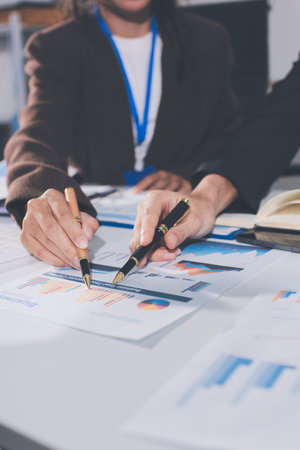 Focused young businessman signing agreement with skilled lawyer in eyeglasses. Concentrated financial advisor showing place for signature on paper contract document to male client at meeting in officeの写真素材