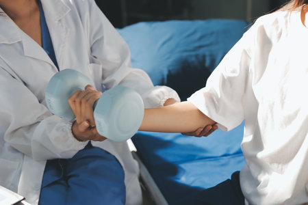 Unrecognizable uses blue hand weight during physical therapy sessionの写真素材