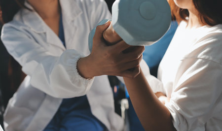 Unrecognizable uses blue hand weight during physical therapy sessionの写真素材