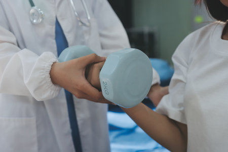 Unrecognizable uses blue hand weight during physical therapy sessionの写真素材