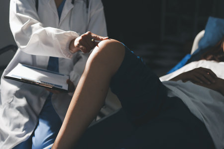 Female doctor hands doing physical therapy By extending the leg and knee of a male patientの写真素材