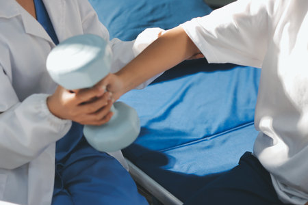 Unrecognizable uses blue hand weight during physical therapy sessionの写真素材