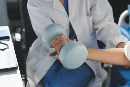 Unrecognizable uses blue hand weight during physical therapy sessionの写真素材