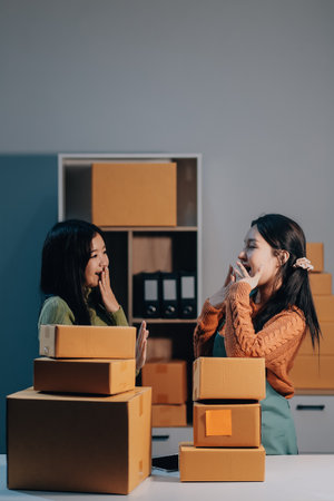 Startup SME small business entrepreneur of freelance Asian woman wearing apron using laptop and box to receive and review orders online to prepare to pack sell to customers, online sme business ideas.の写真素材
