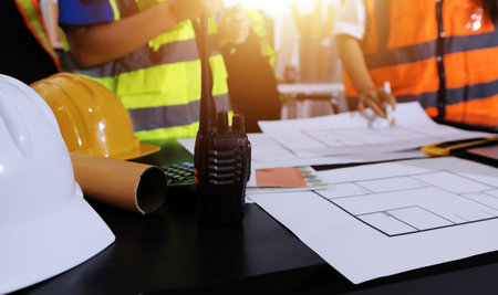 Closeup of team of industrial engineers meeting analyze machinery blueprints consult project on table in manufacturing factory. Working in manufacturing plant or production plant.の写真素材