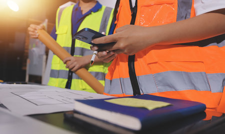 Closeup of team of industrial engineers meeting analyze machinery blueprints consult project on table in manufacturing factory. Working in manufacturing plant or production plant.の写真素材