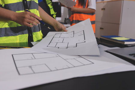 Closeup of team of industrial engineers meeting analyze machinery blueprints consult project on table in manufacturing factory. Working in manufacturing plant or production plant.の写真素材