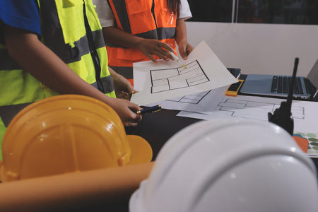Closeup of team of industrial engineers meeting analyze machinery blueprints consult project on table in manufacturing factory. Working in manufacturing plant or production plant.の写真素材