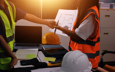 Closeup of team of industrial engineers meeting analyze machinery blueprints consult project on table in manufacturing factory. Working in manufacturing plant or production plant.の写真素材