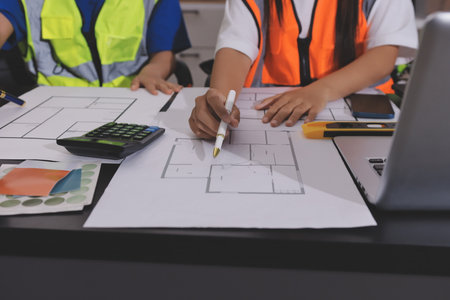 Closeup of team of industrial engineers meeting analyze machinery blueprints consult project on table in manufacturing factory. Working in manufacturing plant or production plant.の写真素材