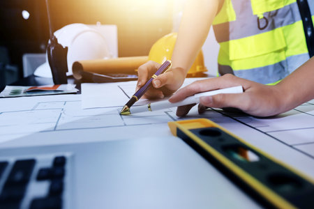 Closeup of team of industrial engineers meeting analyze machinery blueprints consult project on table in manufacturing factory. Working in manufacturing plant or production plant.の写真素材
