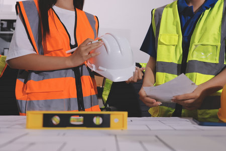 Closeup of team of industrial engineers meeting analyze machinery blueprints consult project on table in manufacturing factory. Working in manufacturing plant or production plant.の写真素材